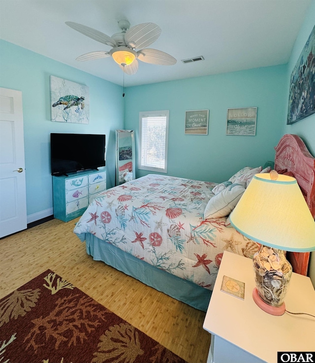 bedroom with baseboards, wood finished floors, visible vents, and a ceiling fan