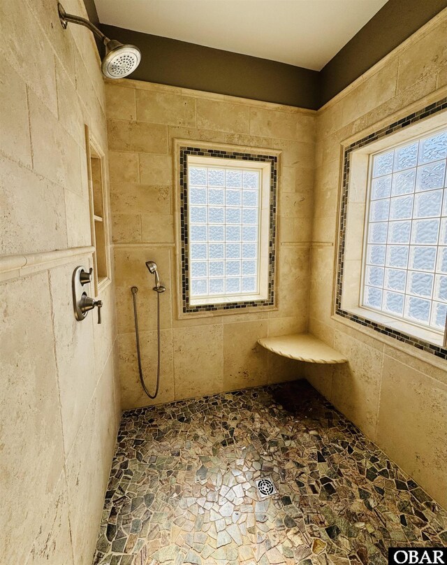 bathroom featuring a wealth of natural light, stone finish floor, and tiled shower