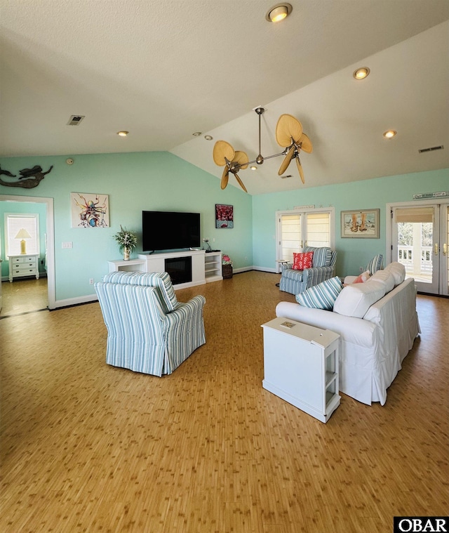 living area with a ceiling fan, lofted ceiling, light wood-type flooring, and visible vents