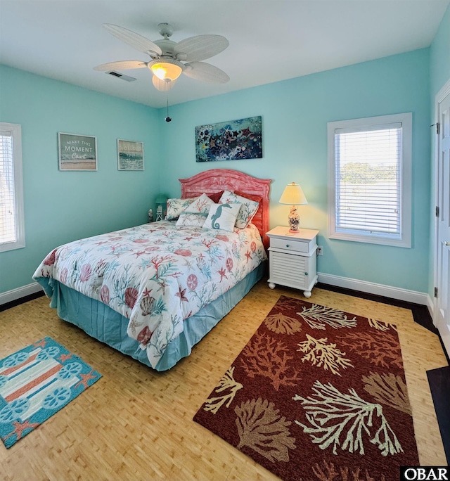 bedroom with multiple windows, baseboards, and wood finished floors