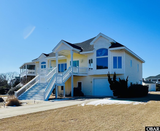 view of front of house with covered porch, stairway, an attached garage, and a front yard