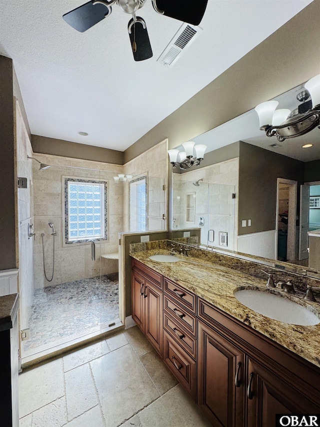 bathroom with double vanity, a shower stall, visible vents, and a sink