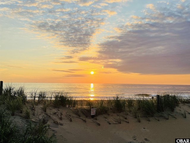 nature at dusk featuring a water view and a view of the beach