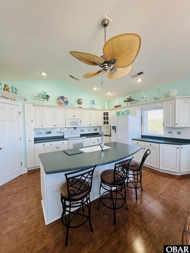 kitchen with white appliances, dark countertops, a sink, and white cabinetry