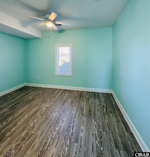 empty room featuring dark wood-style floors, a ceiling fan, and baseboards