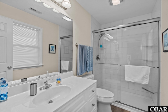 full bathroom with toilet, a stall shower, visible vents, and vanity