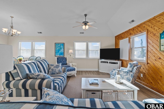 living area with wood walls, plenty of natural light, and visible vents