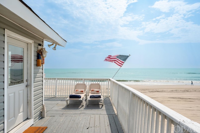 wooden deck with a water view and a beach view