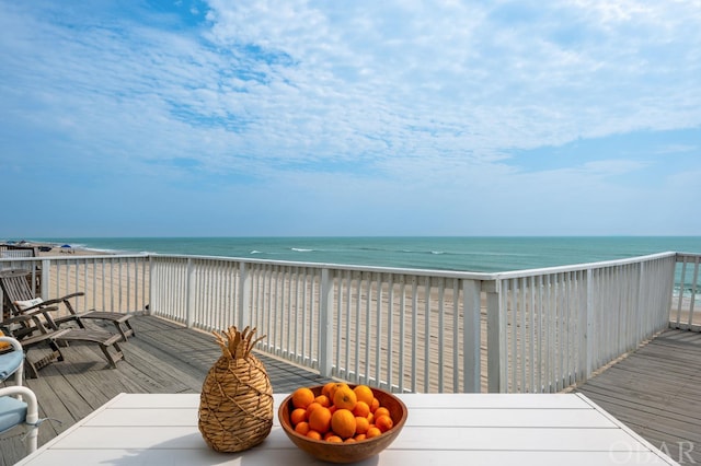 wooden deck with a water view and a view of the beach