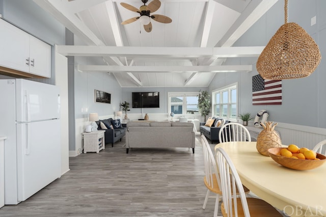 dining space with light wood-style floors, ceiling fan, and lofted ceiling with beams