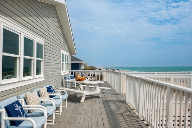 wooden deck featuring a water view and a view of the beach