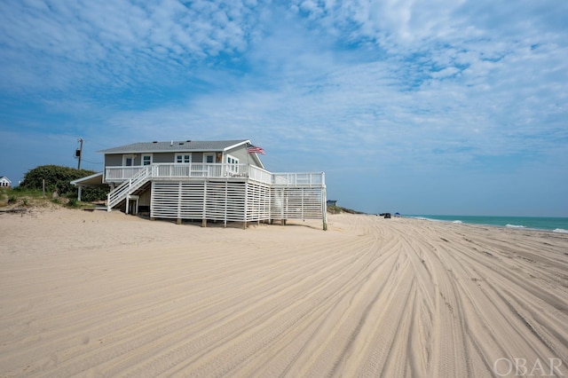 exterior space featuring a view of the beach and a deck with water view