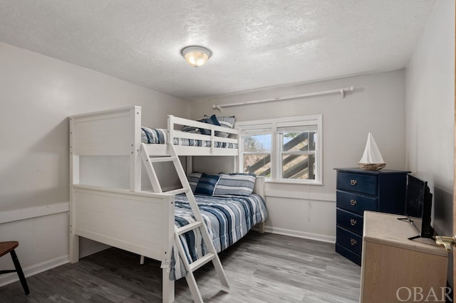 bedroom featuring a textured ceiling, baseboards, and wood finished floors