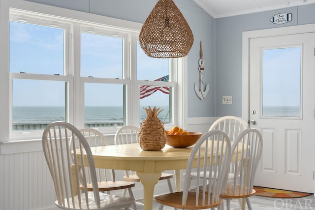 dining space featuring a water view, ornamental molding, and wainscoting