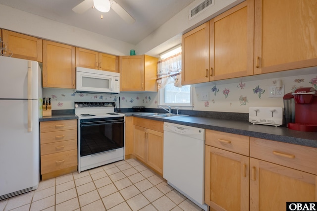 kitchen featuring light tile patterned flooring, white appliances, a sink, visible vents, and dark countertops