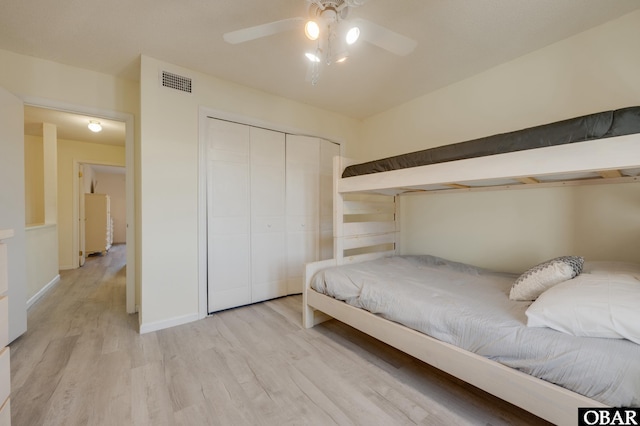 bedroom featuring light wood-style floors, ceiling fan, visible vents, and a closet