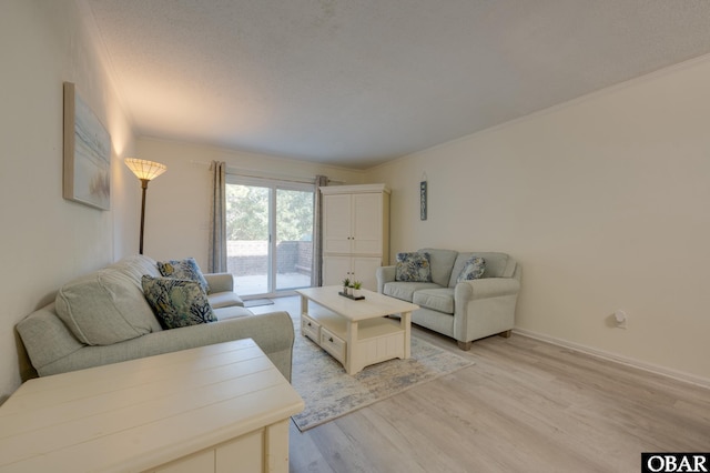 living room with light wood-type flooring, baseboards, and a textured ceiling