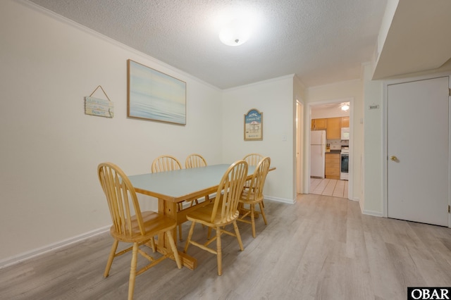 dining room with light wood-style flooring, a textured ceiling, baseboards, and crown molding