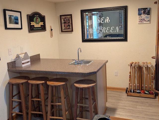 bar with wet bar, a sink, baseboards, and wood finished floors