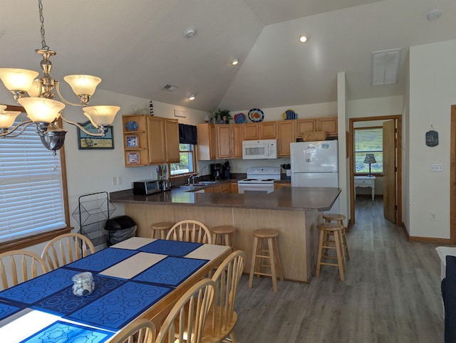 kitchen with pendant lighting, a breakfast bar area, dark countertops, white appliances, and a peninsula