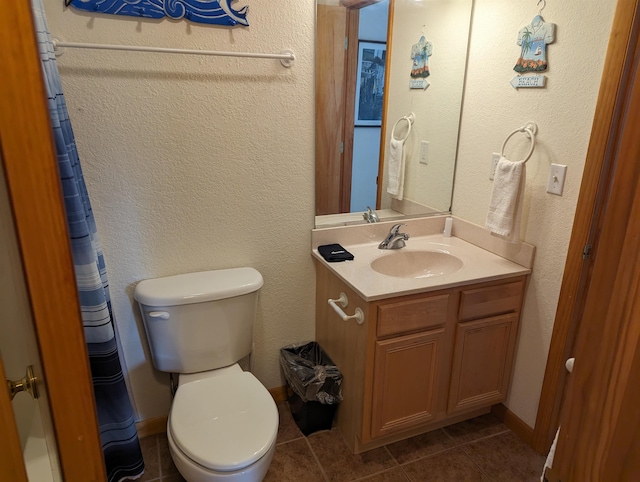 bathroom featuring tile patterned flooring, a textured wall, vanity, and toilet