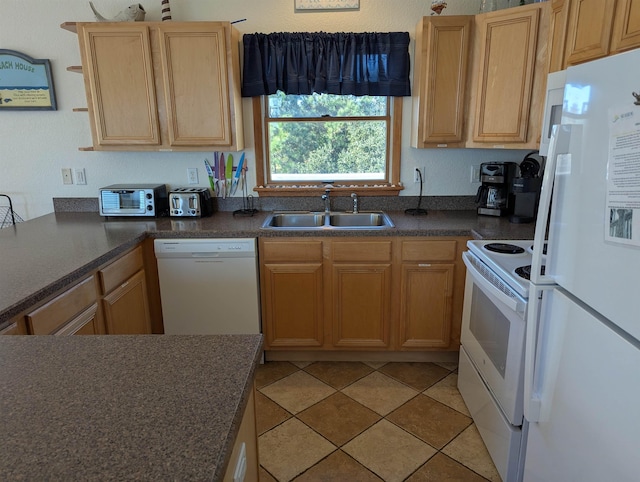 kitchen with dark countertops, white appliances, light brown cabinets, and a sink