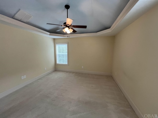 empty room with baseboards, visible vents, ceiling fan, a tray ceiling, and crown molding