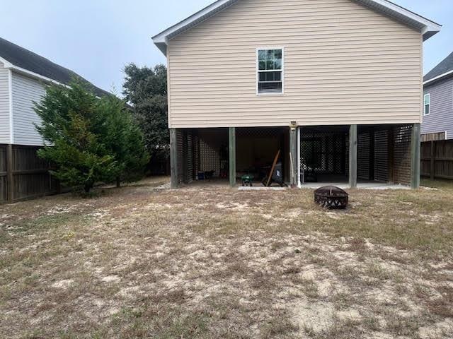 view of side of home featuring a carport, an outdoor fire pit, and fence