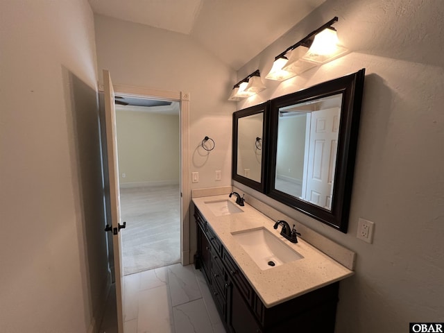 full bath with vaulted ceiling, marble finish floor, a sink, and double vanity