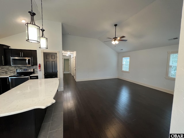 kitchen featuring electric range oven, stainless steel microwave, decorative light fixtures, a center island, and dark cabinetry