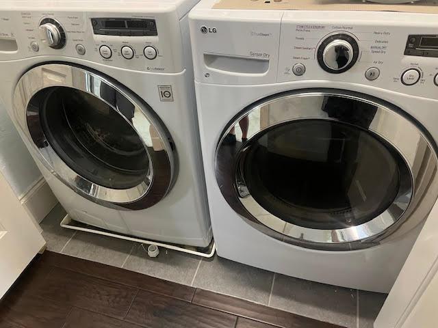 washroom featuring washing machine and dryer, laundry area, and dark tile patterned flooring