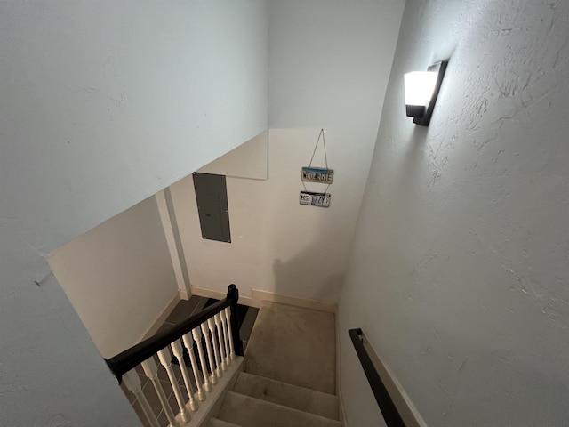 stairs featuring a textured wall and electric panel