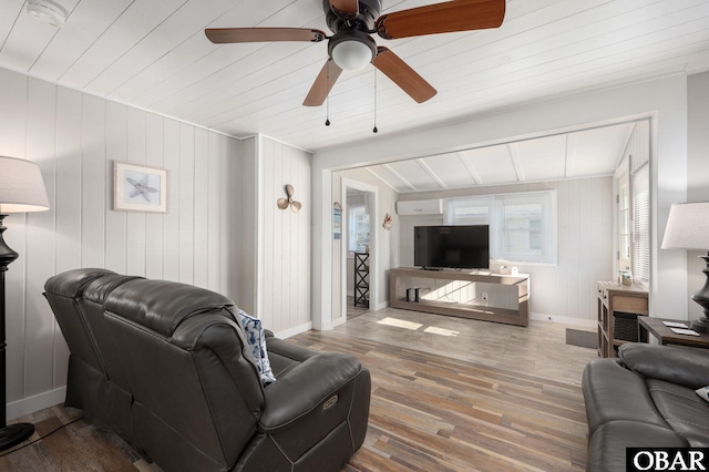 living room with ceiling fan, baseboards, and wood finished floors