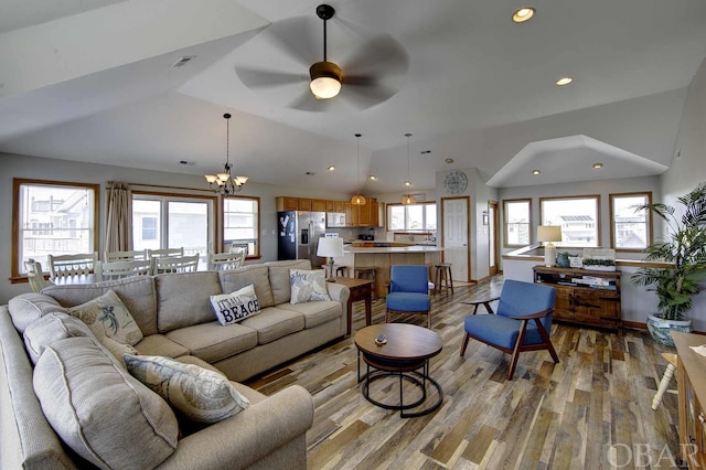 living room with lofted ceiling, light wood-style floors, ceiling fan with notable chandelier, and recessed lighting