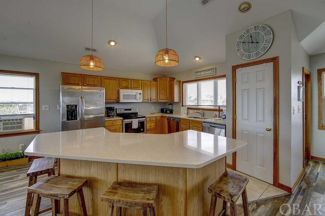 kitchen with visible vents, stainless steel appliances, light countertops, a kitchen bar, and pendant lighting