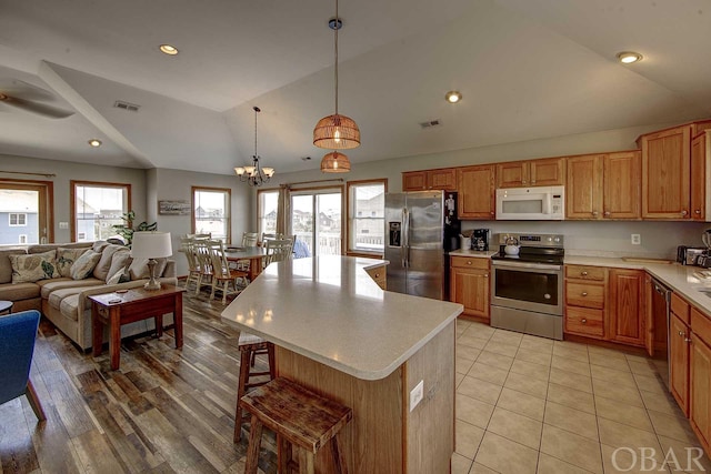 kitchen featuring stainless steel appliances, open floor plan, hanging light fixtures, light countertops, and a center island