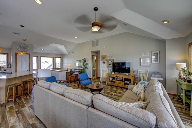 living area with lofted ceiling, visible vents, dark wood finished floors, and a ceiling fan