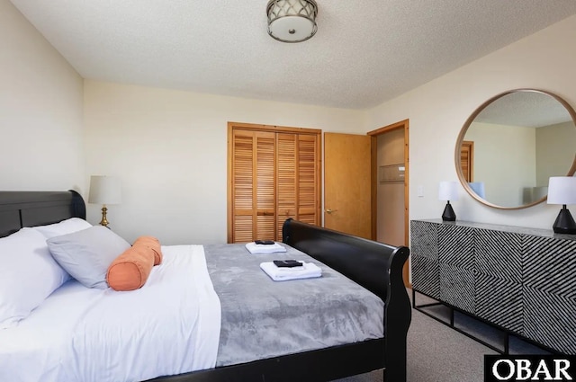 bedroom with a textured ceiling, carpet floors, and a closet