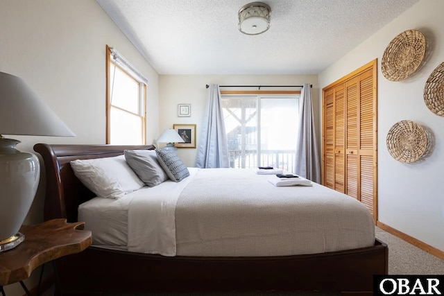 carpeted bedroom with a textured ceiling, a closet, and baseboards