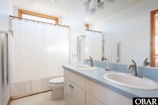 bathroom with a sink, toilet, and double vanity