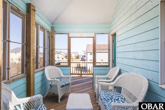 sunroom with a residential view, vaulted ceiling, and a wealth of natural light