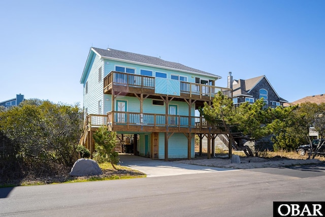 coastal inspired home with a carport, stairway, and driveway