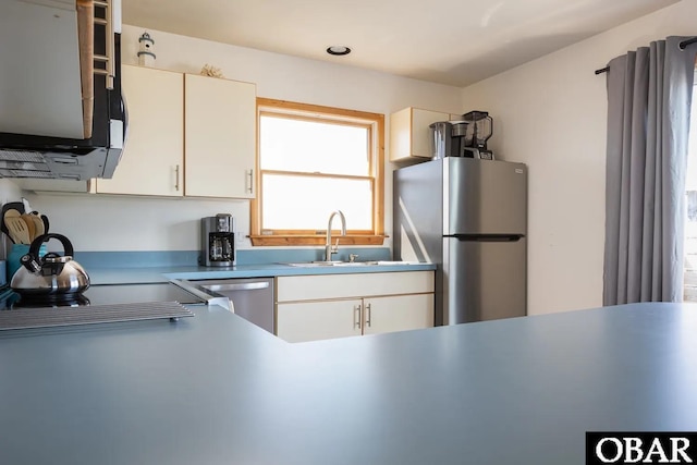 kitchen with appliances with stainless steel finishes, light countertops, white cabinetry, and a sink