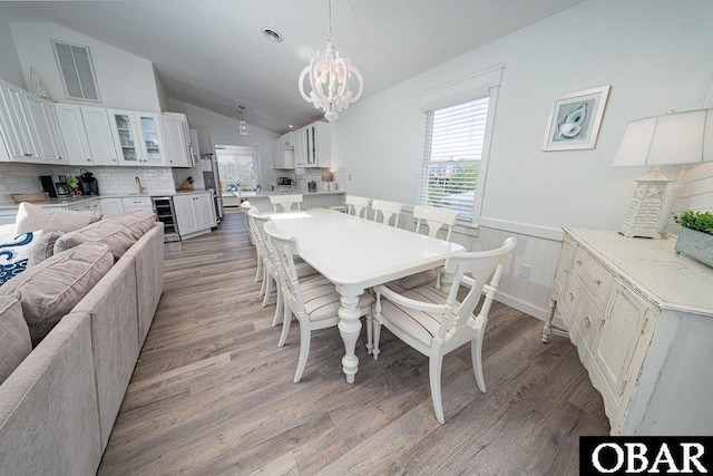 756 Mariner Dr Lot 2, Corolla, NC 27927 - dining area with wine cooler, a chandelier, light wood-type flooring, a wainscoted wall, and lofted ceiling