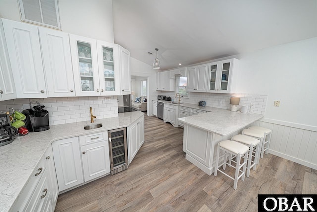 756 Mariner Dr Lot 2, Corolla, NC 27927 - kitchen with beverage cooler, a breakfast bar area, light wood-style floors, a sink, and white cabinets
