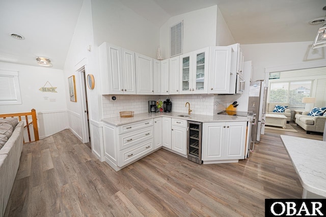 756 Mariner Dr Lot 2, Corolla, NC 27927 - kitchen featuring beverage cooler, vaulted ceiling, a sink, light wood-style floors, and white cabinets