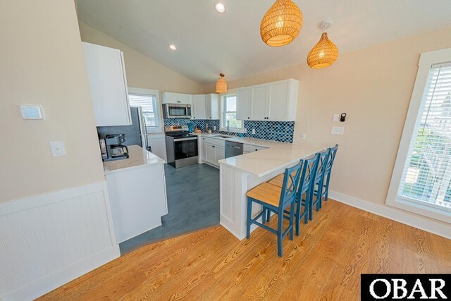 25259 Sea Isle Hills Dr Lot 7, Waves, NC 27982 - kitchen featuring appliances with stainless steel finishes, tasteful backsplash, white cabinetry, a breakfast bar, and light wood-style floors