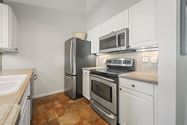 kitchen featuring a sink, white cabinetry, light countertops, appliances with stainless steel finishes, and backsplash