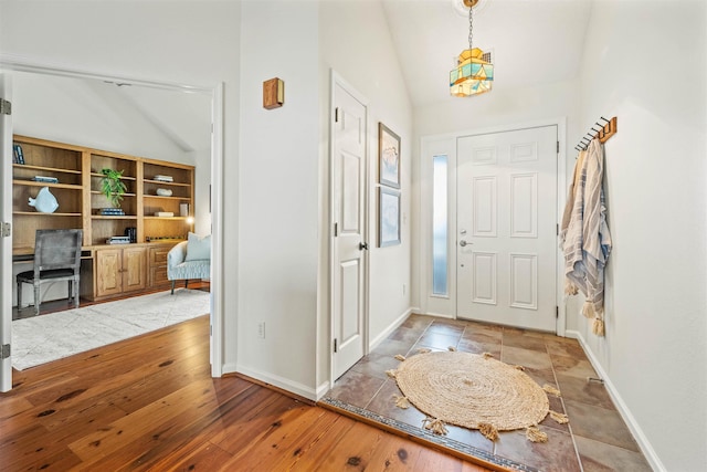 foyer entrance featuring lofted ceiling, baseboards, and wood finished floors