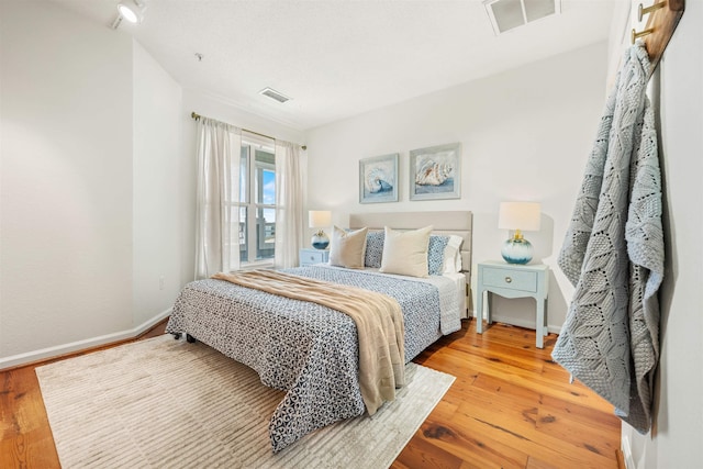 bedroom featuring wood finished floors, visible vents, and baseboards